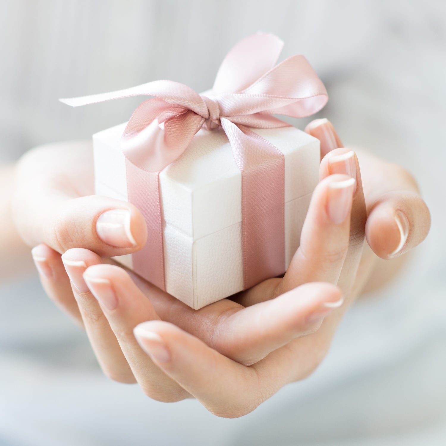 Fotomotiv Gutscheine - Gecshenk mit rosa Schleife in weiblichen Händen