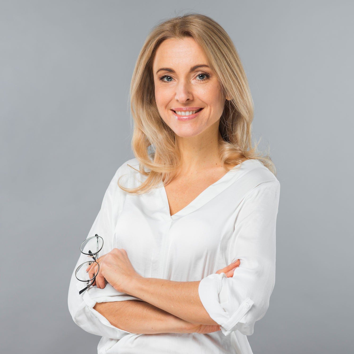 Portrait einer lächelnden blonden Frau mit Brille in der Hand